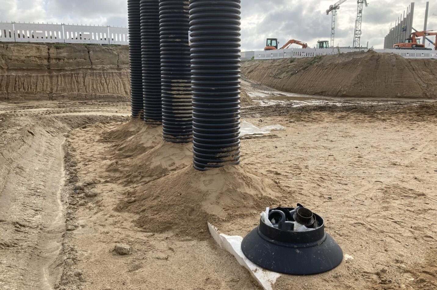 Installierte Quadro-Control-Schächte für die Kontrolle und Wartung der Rigolenanlage im Bahnwerk Cottbus, umgeben von Erdarbeiten und Baukränen.