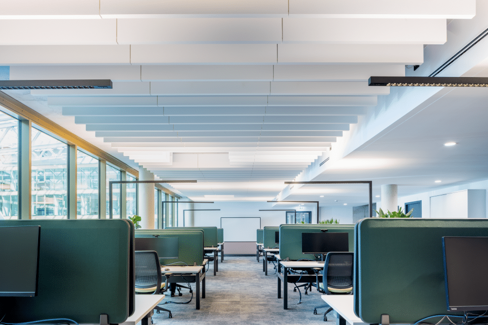 Großraumbüro mit Akustikelementen an der Decke und großzügiger Verglasung.