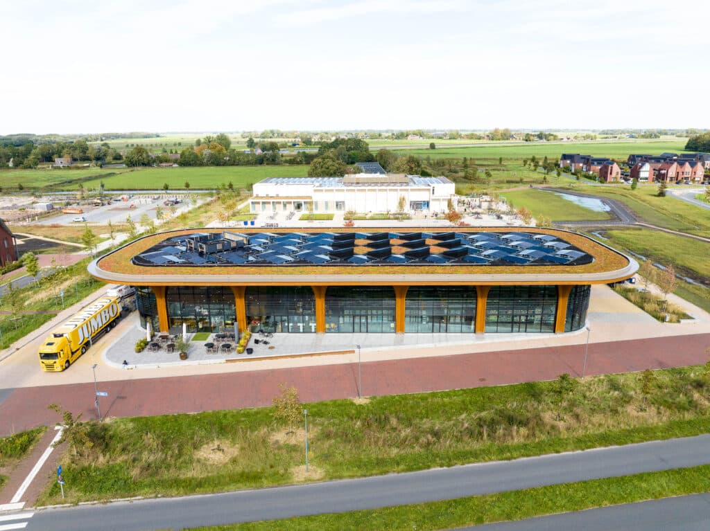 Drohnenaufnahme des Superhub Meerstad mit begrünter Dachfläche und zentralen PV-Modulen, umgeben von Grünflächen und Wohngebäuden.