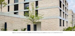 Detailansicht der Kalksteinfassade eines Wohn- und Bürogebäudes mit seidenmatter, gespaltener Oberfläche.