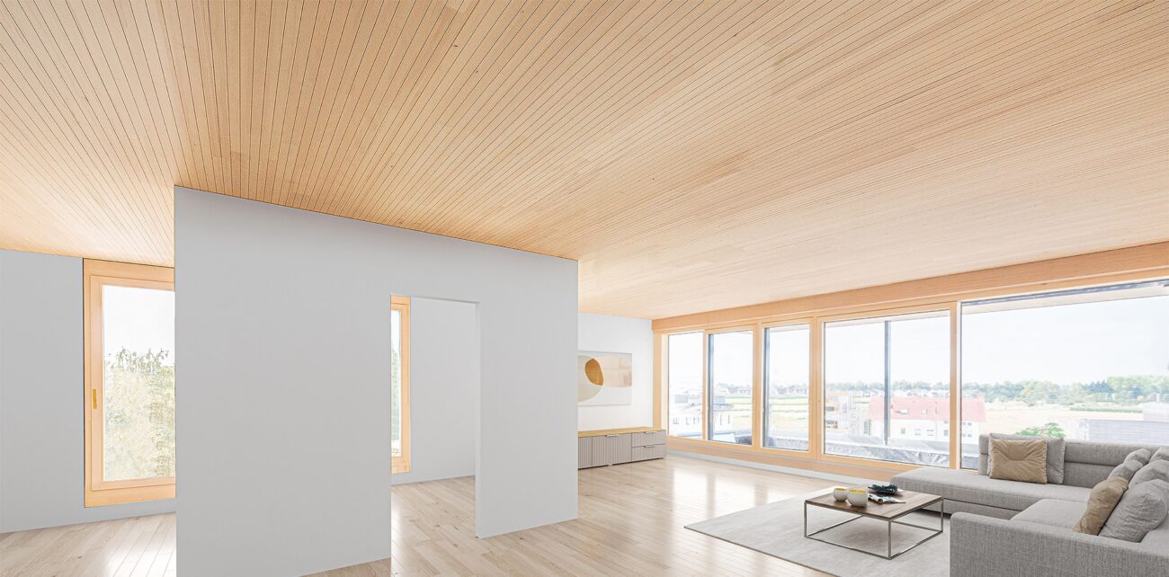 Helles Wohnzimmer mit großer Fensterfront und integrierter best wood CLT BOX Decke in FS Akustik Design.