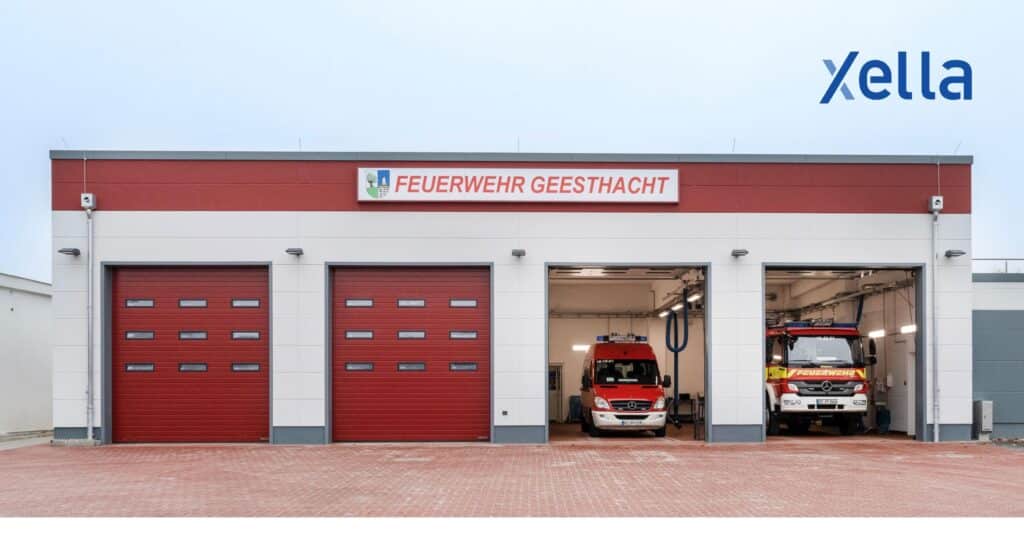 Neubau der Feuerwache Geesthacht mit modernen roten Toren und Einsatzfahrzeugen, errichtet mit Xella Baustofflösungen.