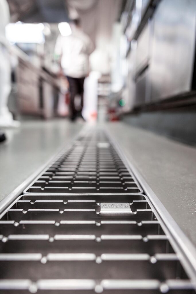 Nahaufnahme einer Edelstahl-Kastenrinne im Küchenboden – ACO System mit hoher Belastbarkeit und optimaler Reinigungsfreundlichkeit.