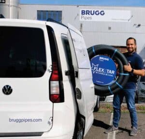 Mitarbeiter vor BRUGG Pipes Gebäude mit FLEXSTAR Rohrsystem.