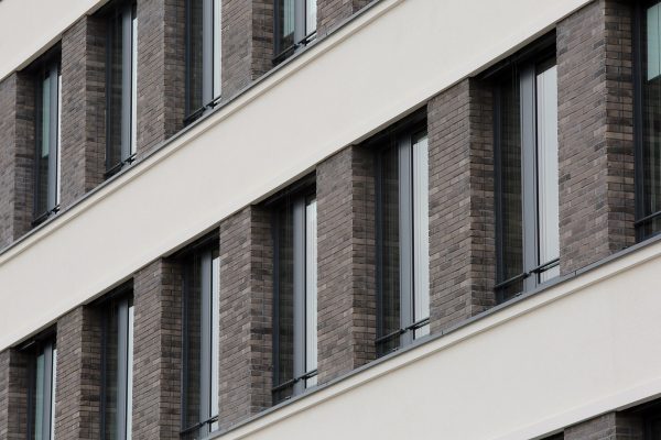 Moderne Kombinationsfassade mit dunklen Riemchen und hellem Putz an einer mehrstöckigen Gebäudefront.