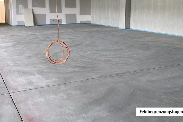 Präzise Feldbegrenzungsfugen im Zementestrich eines weitläufigen Raums im Rohbau zur Rissvermeidung.