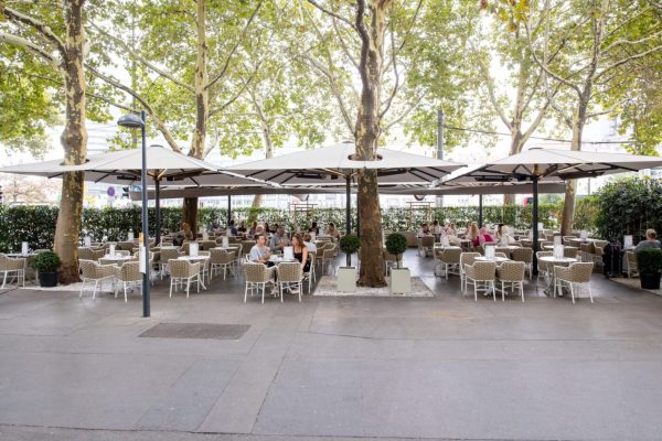 Weiße PALAZZO® Royal Großschirme im Außenbereich der Gelateria Castelletto in Wien unter schattigen Bäumen.