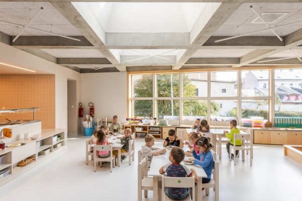Kinder essen in einem hellen Kindergarten mit VELUX Oberlicht-Lösungen für natürliches Tageslicht.