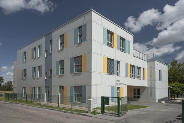 Modernes Gebäude der Grundschule Angermünde mit farbigen Fassadenelementen und dem Hort Abenteuerland.