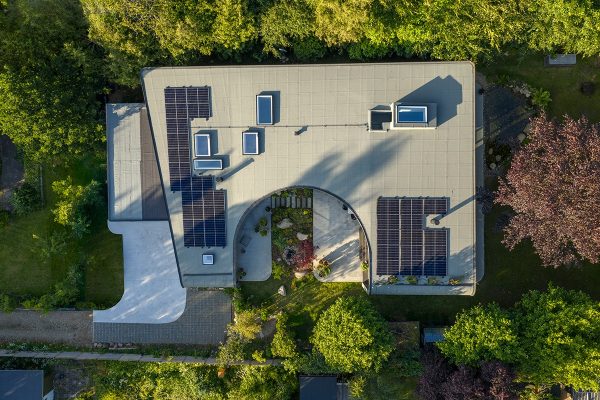 ADA House von mencke&vagnby aus der Vogelperspektive mit Photovoltaikanlage und geschwungenem Innenhof im Grünen.