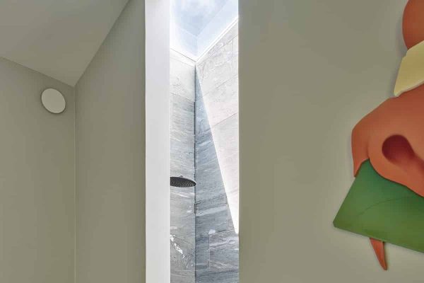 Moderne Dusche mit Natursteinwänden und hellem Oberlicht im ADA House, Architektur von mencke und vagnby.