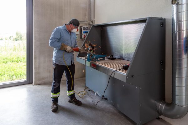 Handwerker bei der Metallbearbeitung an einem ergonomischen ESTA Absaugtisch mit integrierter Absaugung.