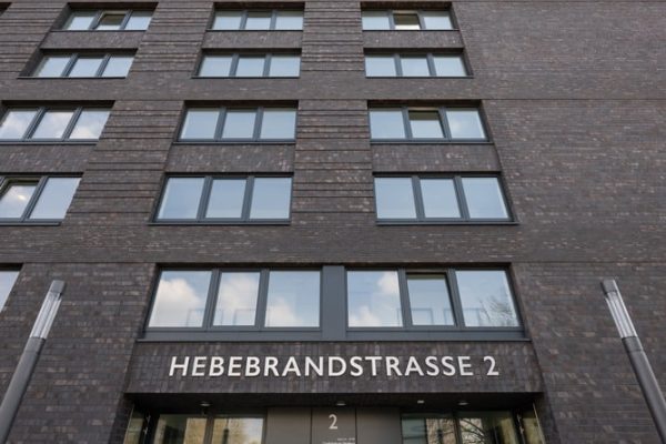 Moderne Außenansicht des PERIGON Hamburg mit dunkler Backsteinfassade und Glaseingang in der Hebebrandstraße.
