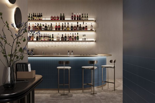 Moderne Bar mit blauer Fliesenoptik und Barhockern, gestaltet mit dem fugenlosen Wandsystem Altro Tegulis.