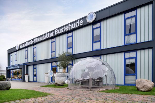 Strandkorb in einer transparenten Kuppel vor dem modernen Gebäude der Strandkorbmanufaktur Buxtehude.