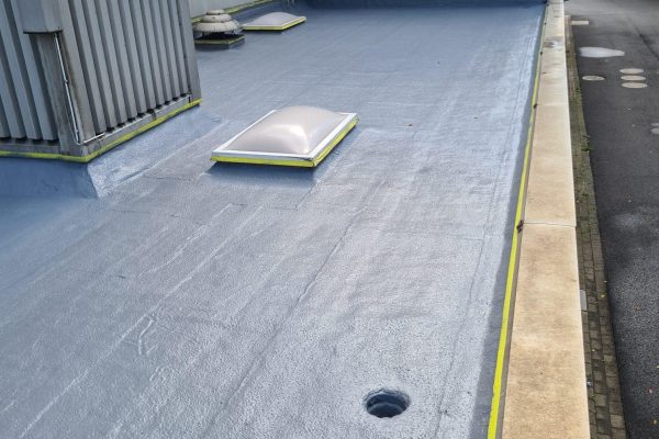 Frisch abgedichtetes Flachdach der SBS Ecoclean Gruppe Monschau mit grauer Beschichtung und Lichtkuppeln.