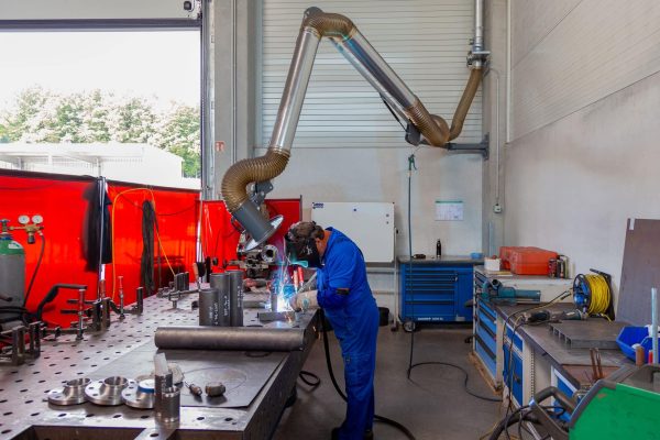 Absaugarme erfassen Schweißrauch punktuell am Werktisch und sind mit einer zentralen Absauganlage verbunden.
