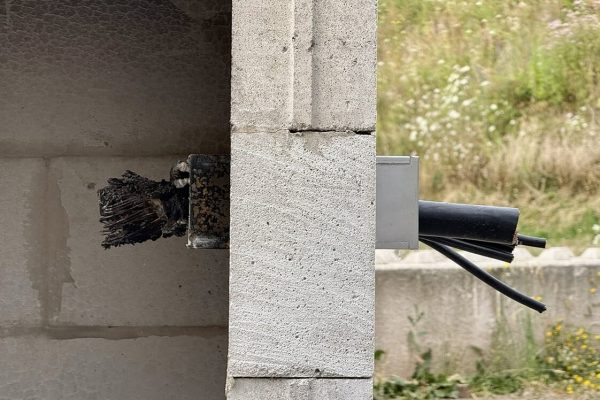Vergleich im Mauerwerk: Links verkohlte Kabel nach einem Brand und rechts unbeschädigte Leitungen in der Wand.