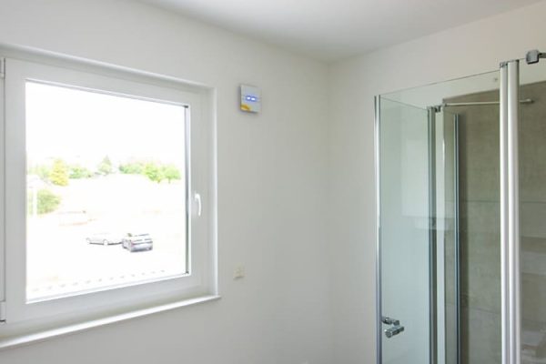 Modernes Badezimmer mit Glasdusche und einem flachen, weißen Decken-Heizelement im Bad an der Decke.