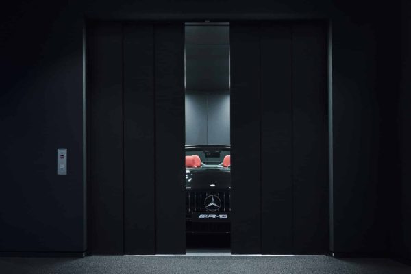 Schwarzer Mercedes-AMG mit roten Sitzen im CARRICO Autoaufzug des modernen AMG Brand Centers in Hamburg.