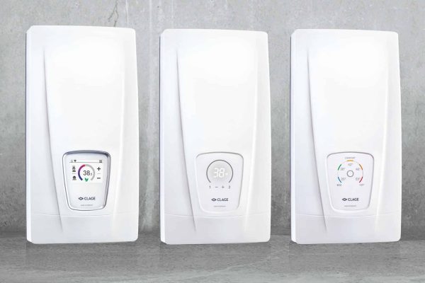 Drei CLAGE Durchlauferhitzer Modelle DSX Touch, DCX Next L und DCX Next nebeneinander an einer grauen Wand.