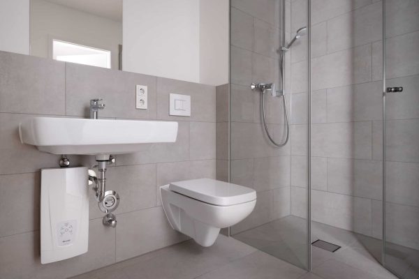 Modernes Badezimmer mit Dusche und WC sowie einem platzsparenden CLAGE Durchlauferhitzer unter dem Waschbecken.