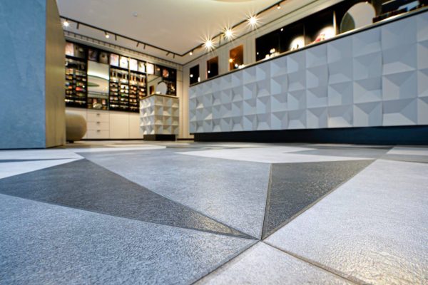 Geometrischer Designbodenbelag Altro Ensemble / M500 in Grau und Weiß in einem modernen Ladengeschäft.