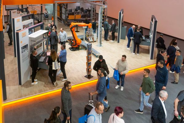 Besucher am OBO Bettermann Messestand Light + Building 2026 mit KUKA Roboterarm und Produktpräsentation.