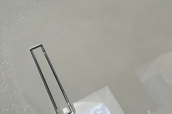 Modernes Entwässerungssystem DallFlex 2.0 in grauem Boden mit Wassertropfen und Spiegelungen.