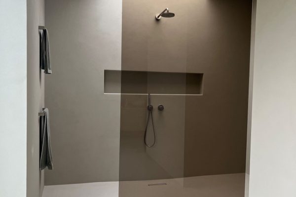 Moderne bodengleiche Dusche mit getönter Glaswand und natürlichem Oberlicht im Dallmer Referenzbad Brilon.