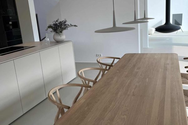 Helle Dallmer Referenz Brilon Küche mit massivem Holztisch und Designerstühlen in minimalistischem Design.