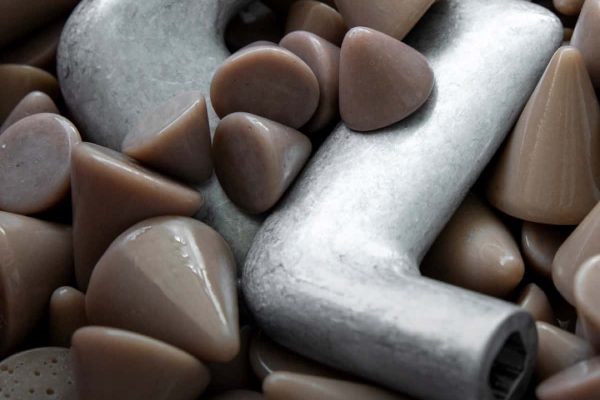 Aluminium-Türdrücker FSB 1291 in einer Trowalisiertrommel mit braunen Schleifsteinen zur Oberflächenveredelung.