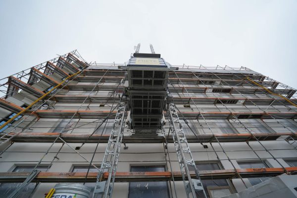 GEDA Passau Lastenaufzug im Einsatz an einem Baugerüst während Sanierungsarbeiten an einem Gebäude.