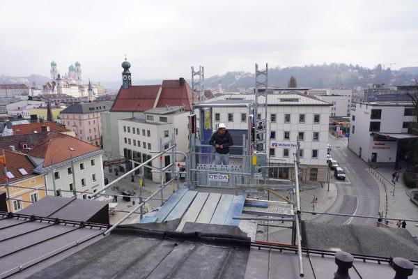 GEDA Passau Transportbühne im Einsatz bei Dacharbeiten mit Blick auf den Passauer Dom und die Altstadt.