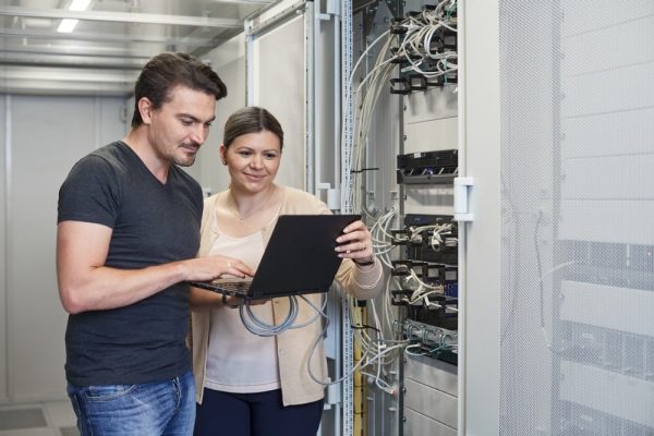 Zwei Techniker steuern smarte Gebäudeautomation am Server für Sicherheit in kritischer Infrastruktur.