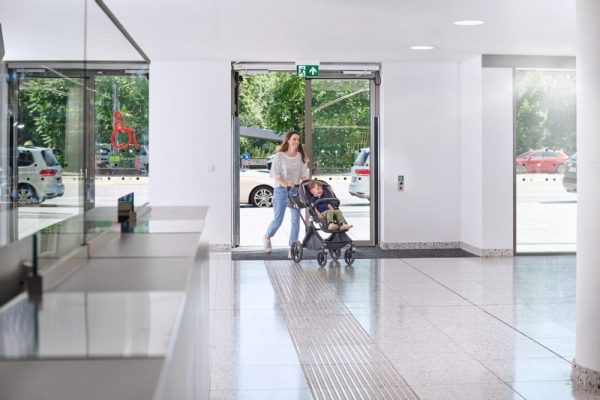 Frau mit Kinderwagen nutzt barrierefreie Türen im Klinikum Stuttgart als Beispiel für barrierefreie Planung.