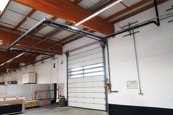Weißes Sektionaltor in einer Industriehalle mit Holzbalken und genügend Platz für das Rolltor zur Installation.