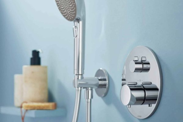 Moderne HANSA EASYTHERM & HANSA AURELIA Duscharmaturen in Chrom an einer hellblauen Wand im Badezimmer.