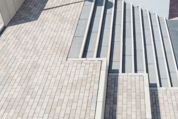 Moderne Betontreppe mit hellen Pflastersteinen, um Höhenunterschiede sicher gestalten zu können.