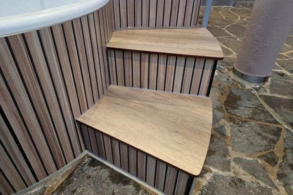 Whirlpool-Treppe in Holzoptik für runde Wände auf rustikalem Steinboden als moderne und saubere Lösung.