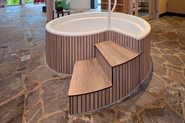 Runder Whirlpool mit Holzverkleidung als saubere Lösung für runde Wände in einem Wellnessbereich.