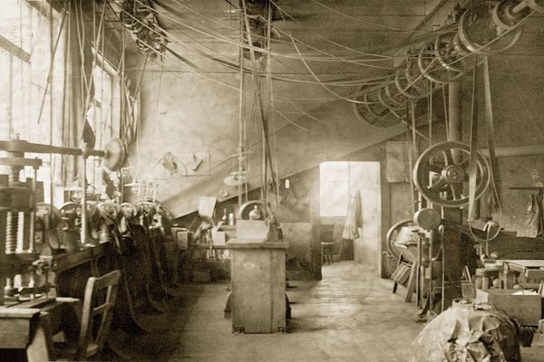 Historische Werkstatt im Fabrikgebäude 1909 mit Riemenantrieben und alten Maschinen zur Metallverarbeitung.