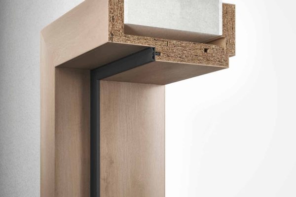 Querschnitt einer Holz-Variantzarge in Eichenoptik mit schwarzer Dichtung an einer weißen Wand.