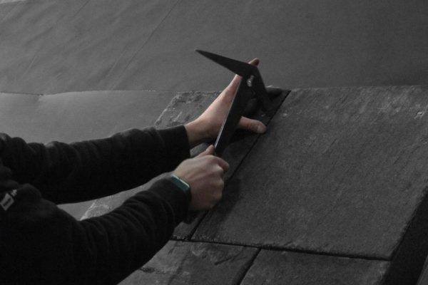 Handwerker nutzt Spezialwerkzeug, um Schieferplatten für ein stilvolles Ergebnis professionell zu bearbeiten.