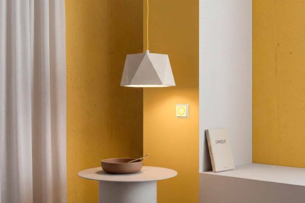 Lichtschalter mit Sonnensymbol zur Zuordnung der Beleuchtung in einem modernen gelben Interieur.