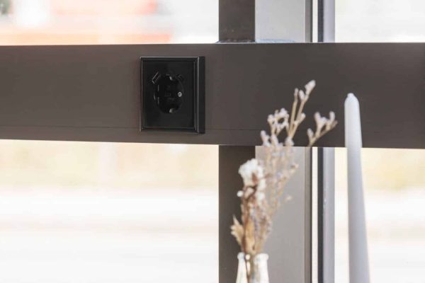 Moderne JUNG USB-Steckdose LS 990 in Graphitschwarz matt, dezent in einen Fensterrahmen integriert.
