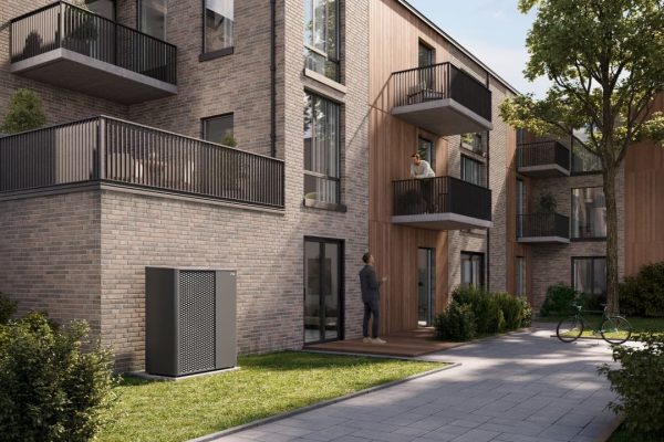 x-change dynamic pro XL Wärmepumpe vor einem modernen Mehrfamilienhaus mit Klinkerfassade und Balkonen.