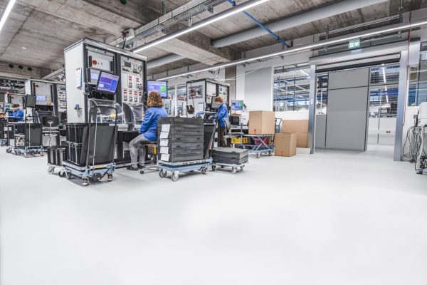 Techniker an Testsystemen in einer modernen Halle mit Bodenbelag gemäß der Anforderungen an ESD-Schutz.