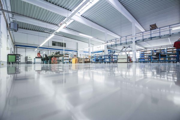 Helle Industriehalle mit glänzendem Bodenbelag durch ESD-Beschichtungssysteme zum Schutz sensibler Elektronik.