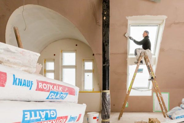 Handwerker auf Leiter bei der Fenstersanierung mit Knauf Rotkalk in System Innendämmung Berlin.